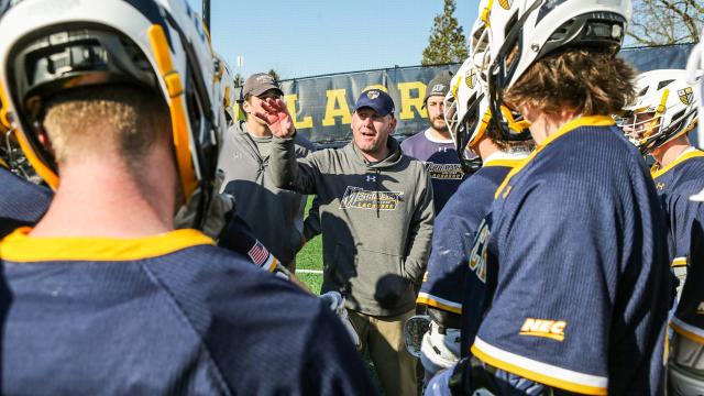 Merrimack men's lacrosse coach Mike Morgan in a team huddle