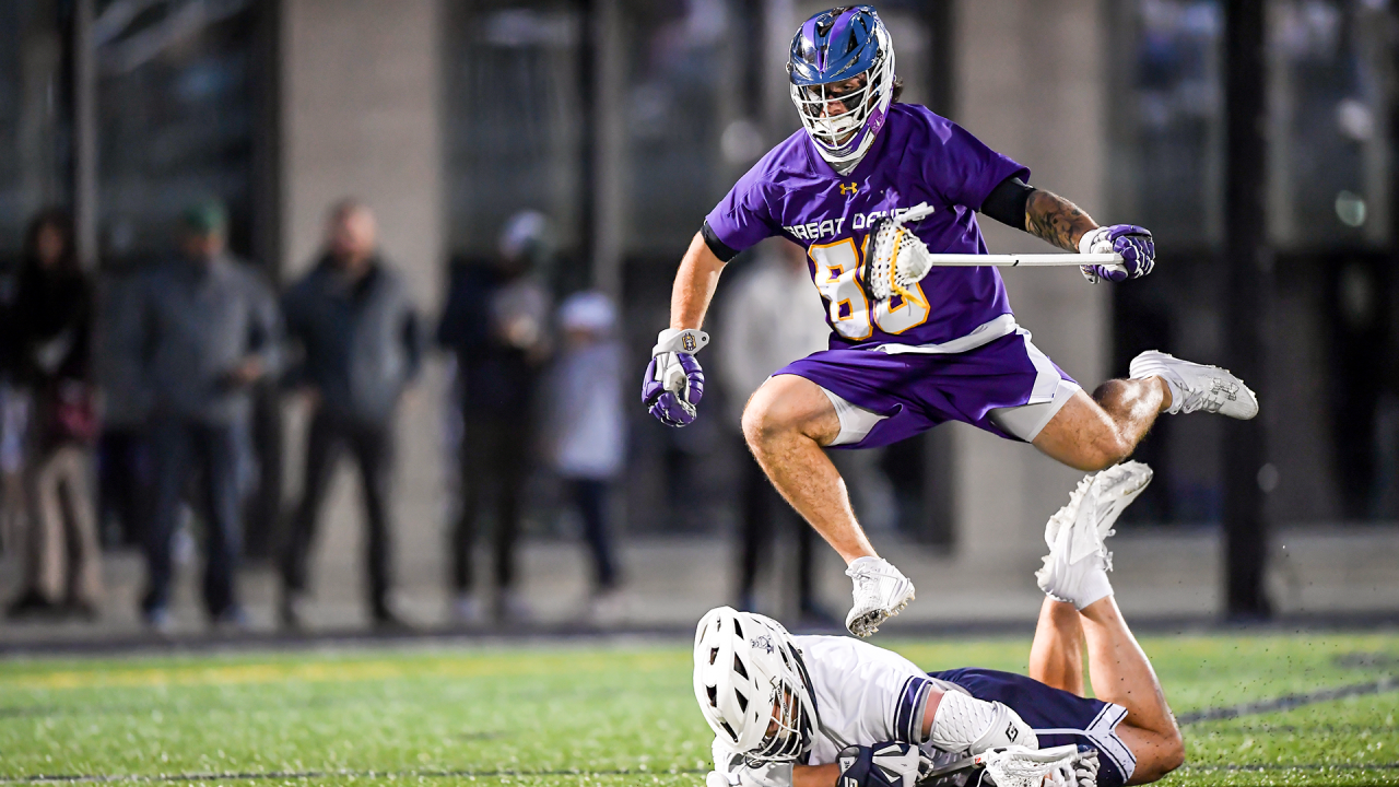 Albany defenseman Jake Piseno hurdles Yale attackman Matt Brandau during the teams' April 19 game in New Haven, Conn.