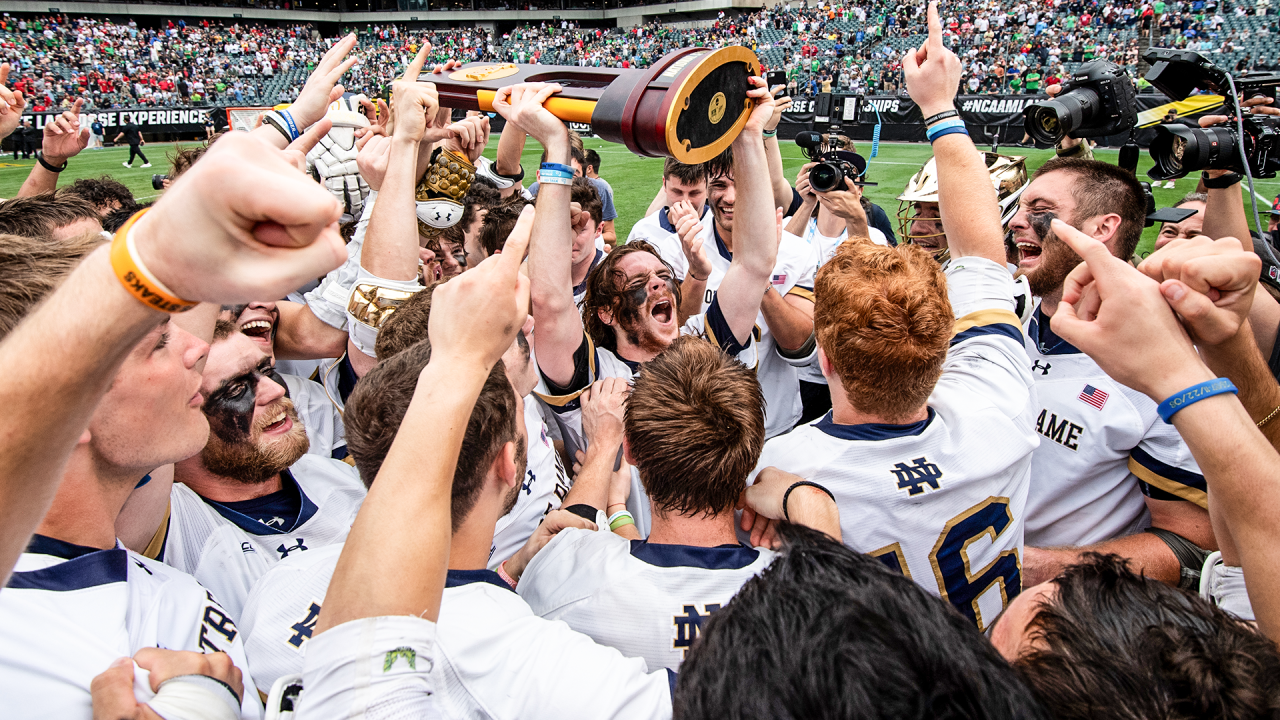 Notre Dame's Pat Kavanagh hoists the walnut and bronze trophy surrounded by teammates celebrating at Lincoln Financial Field in Philadelphia.