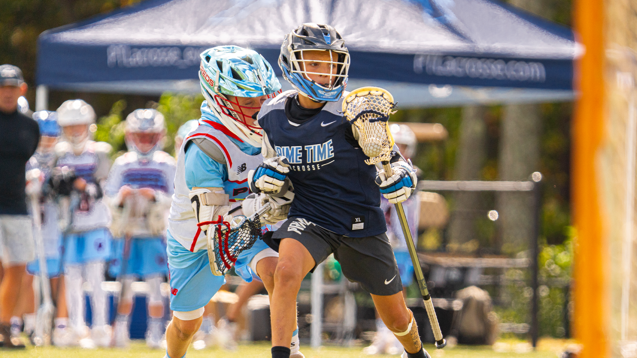 A youth player from Prime Time Lacrosse dodges near the crease.